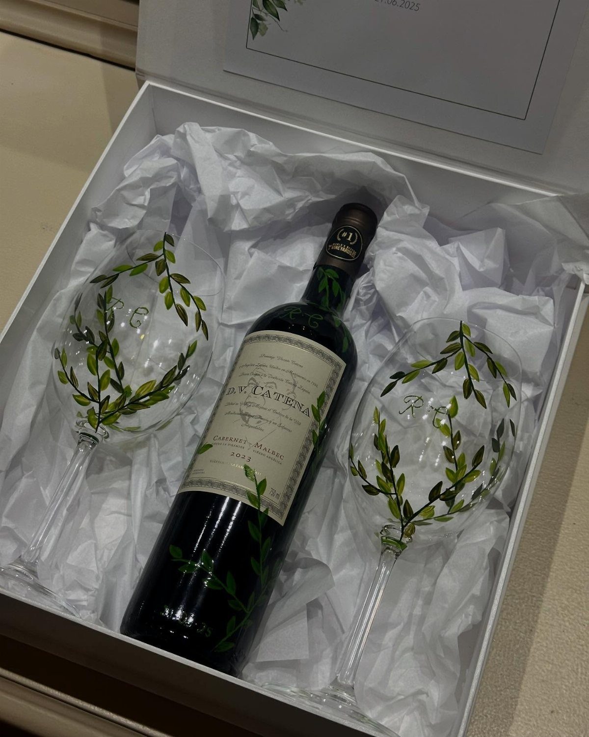 Wine bottle and two decorated wine glasses in a white gift box