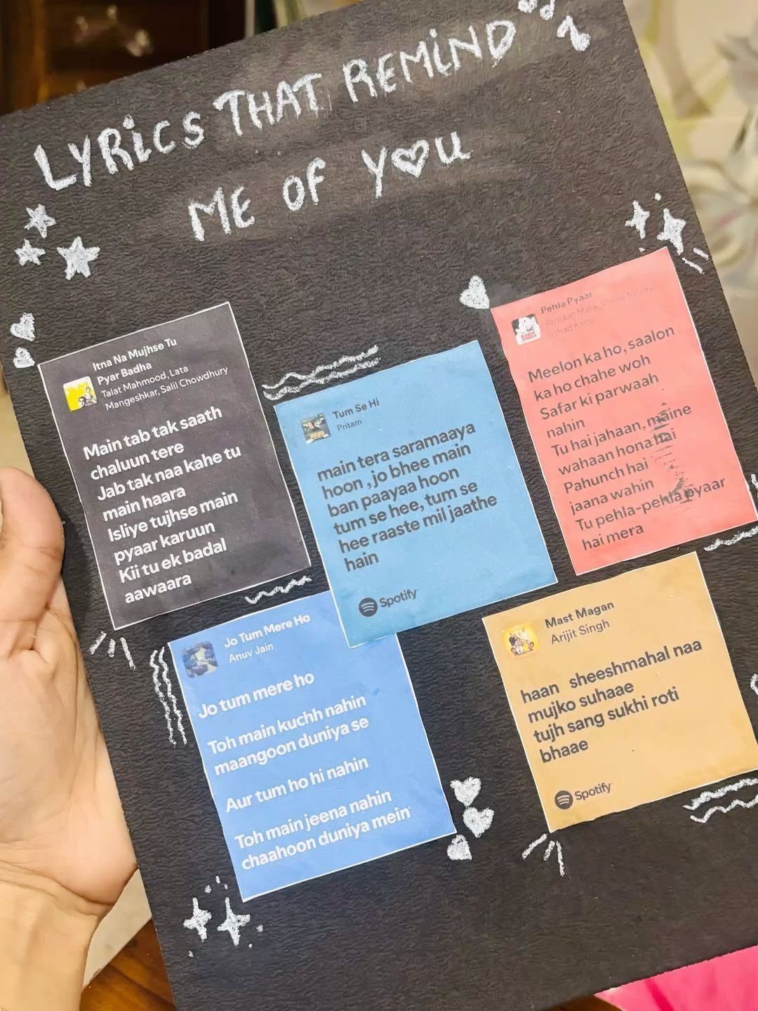 Handmade black poster with colorful cards displaying song lyrics and Spotify logos.