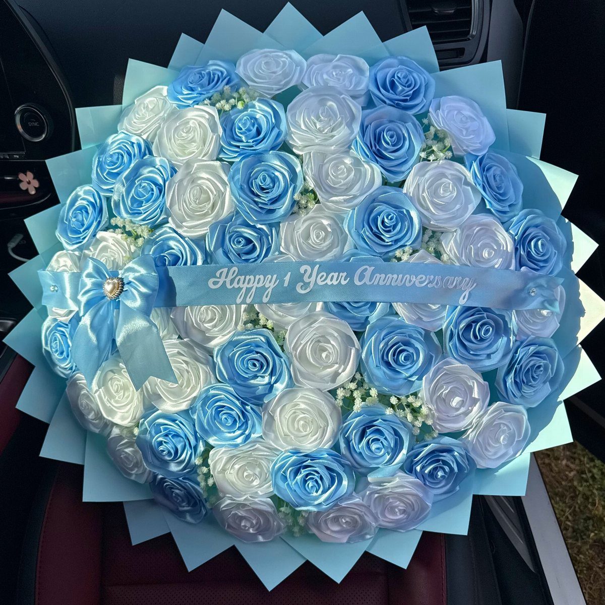 Blue and white satin ribbon rose bouquet with Happy 1 Year Anniversary banner.