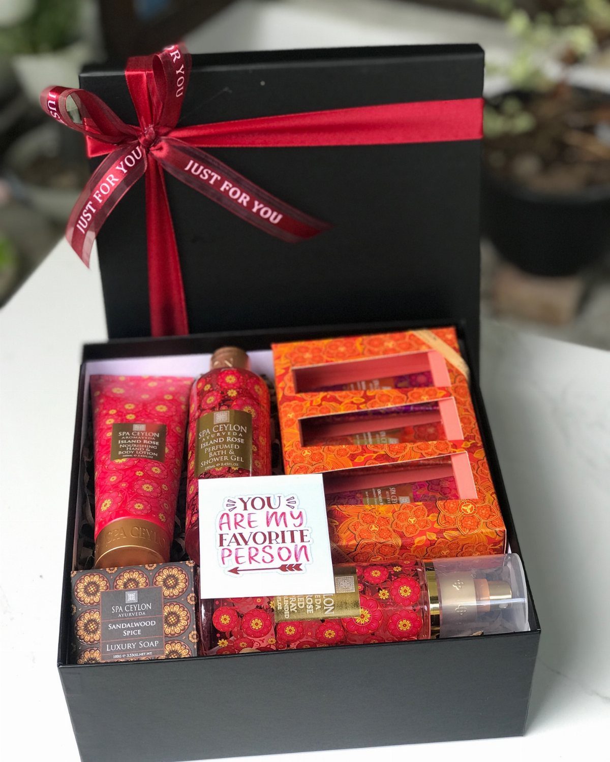 Luxury spa gift set in a black box with red floral toiletries and card.