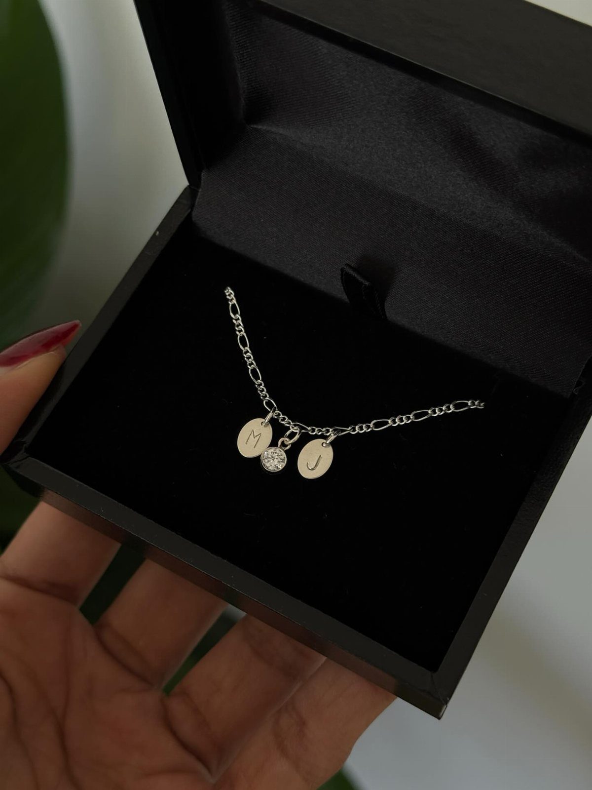Silver necklace with M and J initial pendants in a black jewelry box