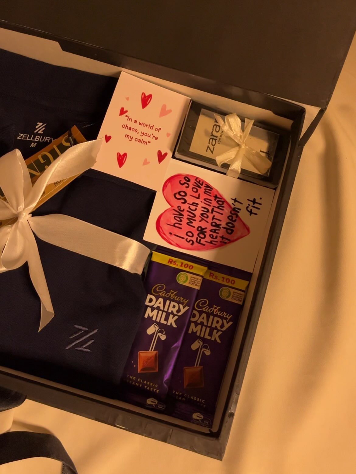 Gift box with navy clothing, chocolate bars, and handwritten love notes for him.