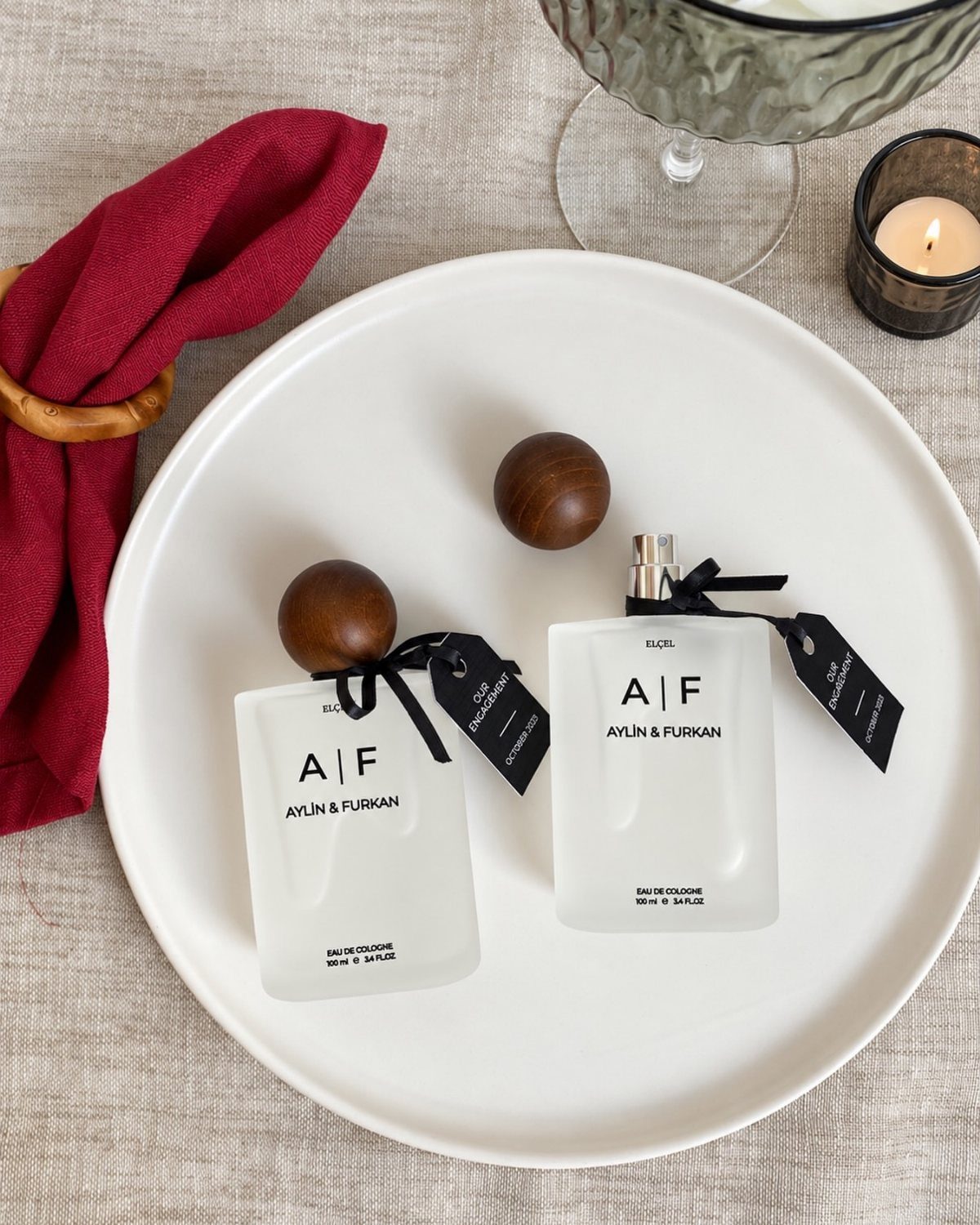 Two personalized frosted glass cologne bottles with black ribbons on a white tray.