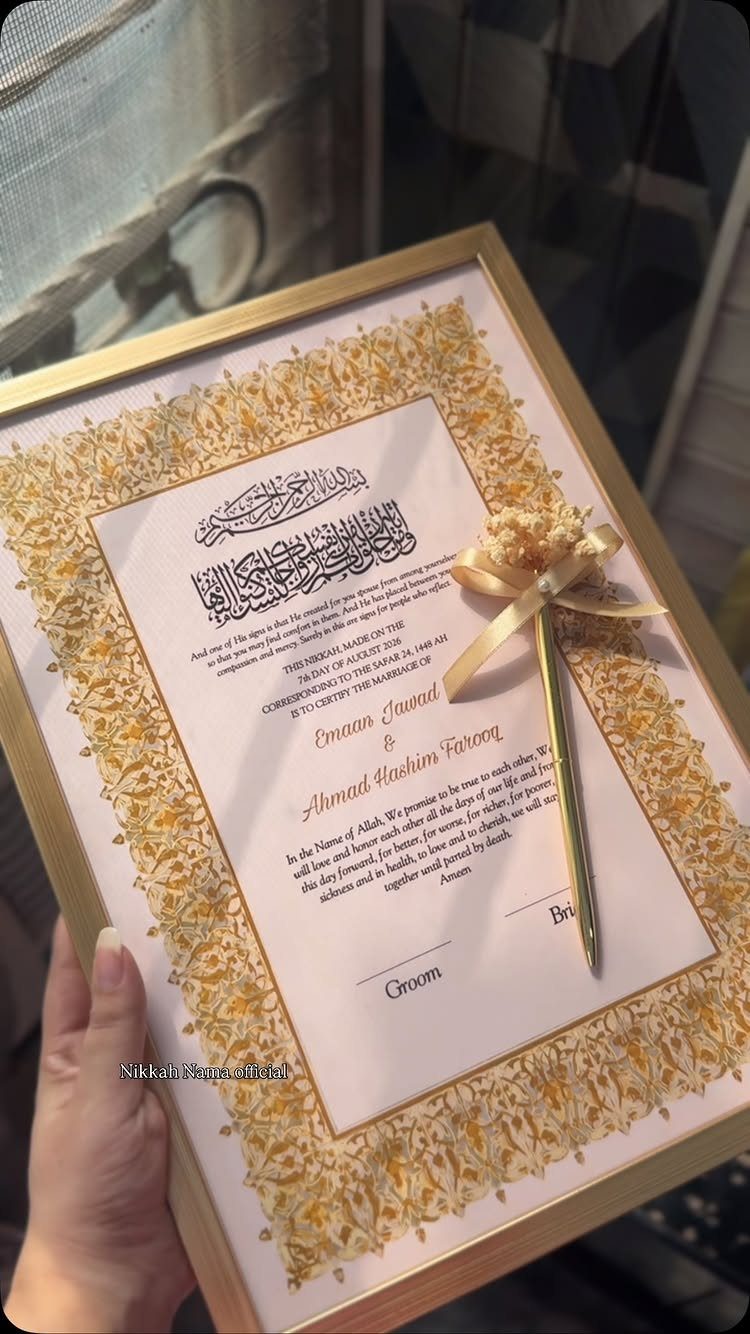 Gold-framed marriage contract with ornate borders and a gold pen with a bow.
