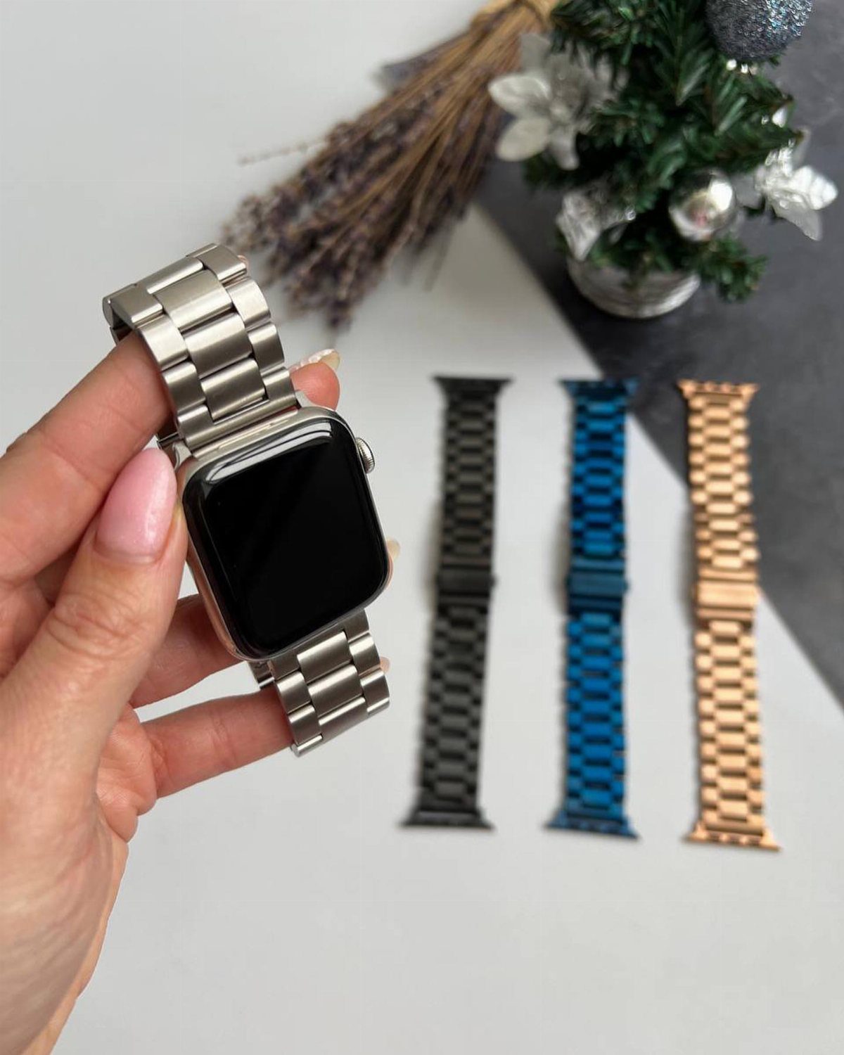 Smartwatch with silver metal band and three alternative colored bands on white surface