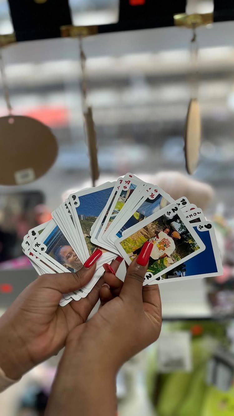 Hands holding a fanned deck of custom playing cards featuring personal photographs.