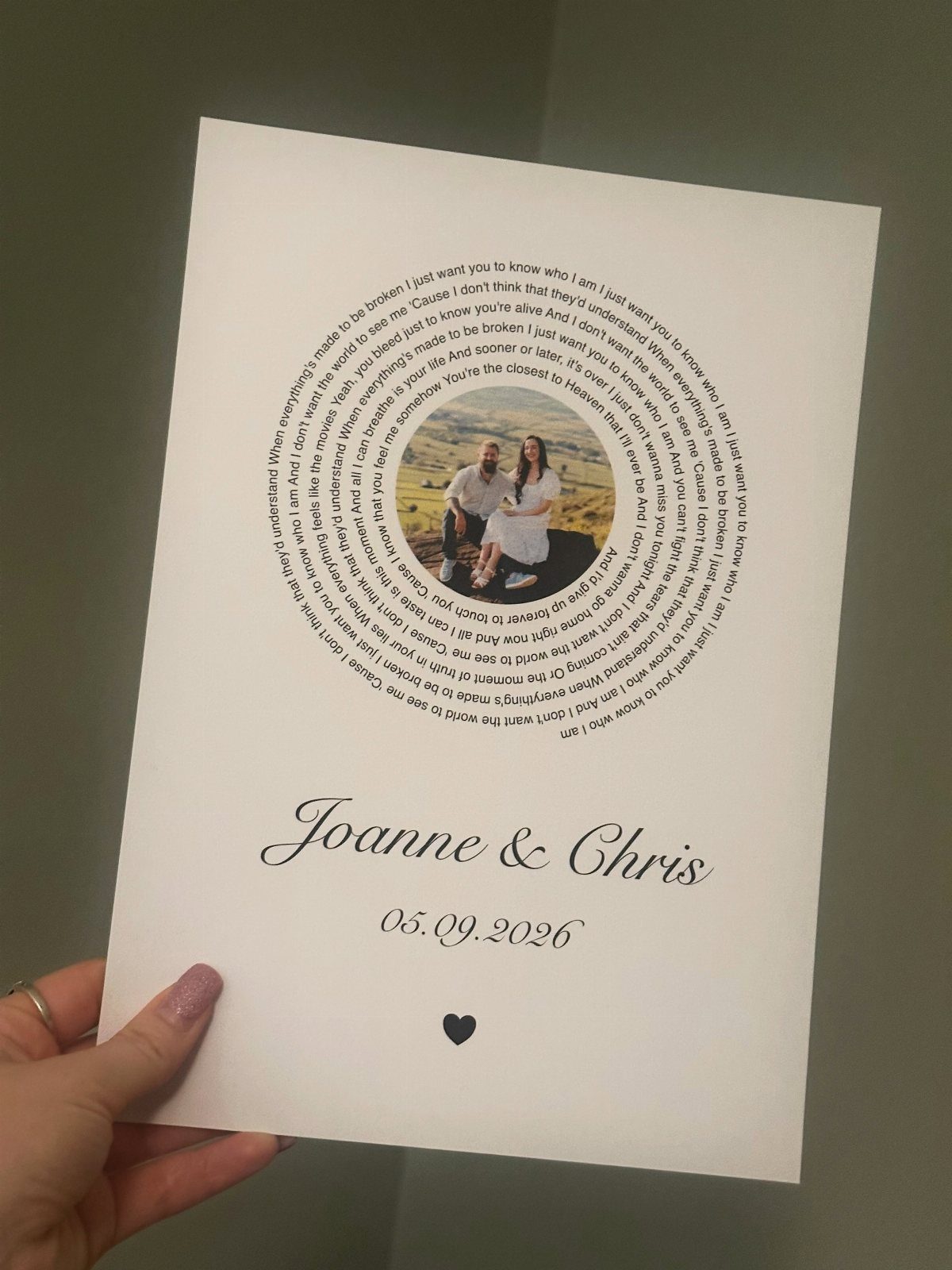 Printed lyrics arranged in a circle around a couple's photo with names below.