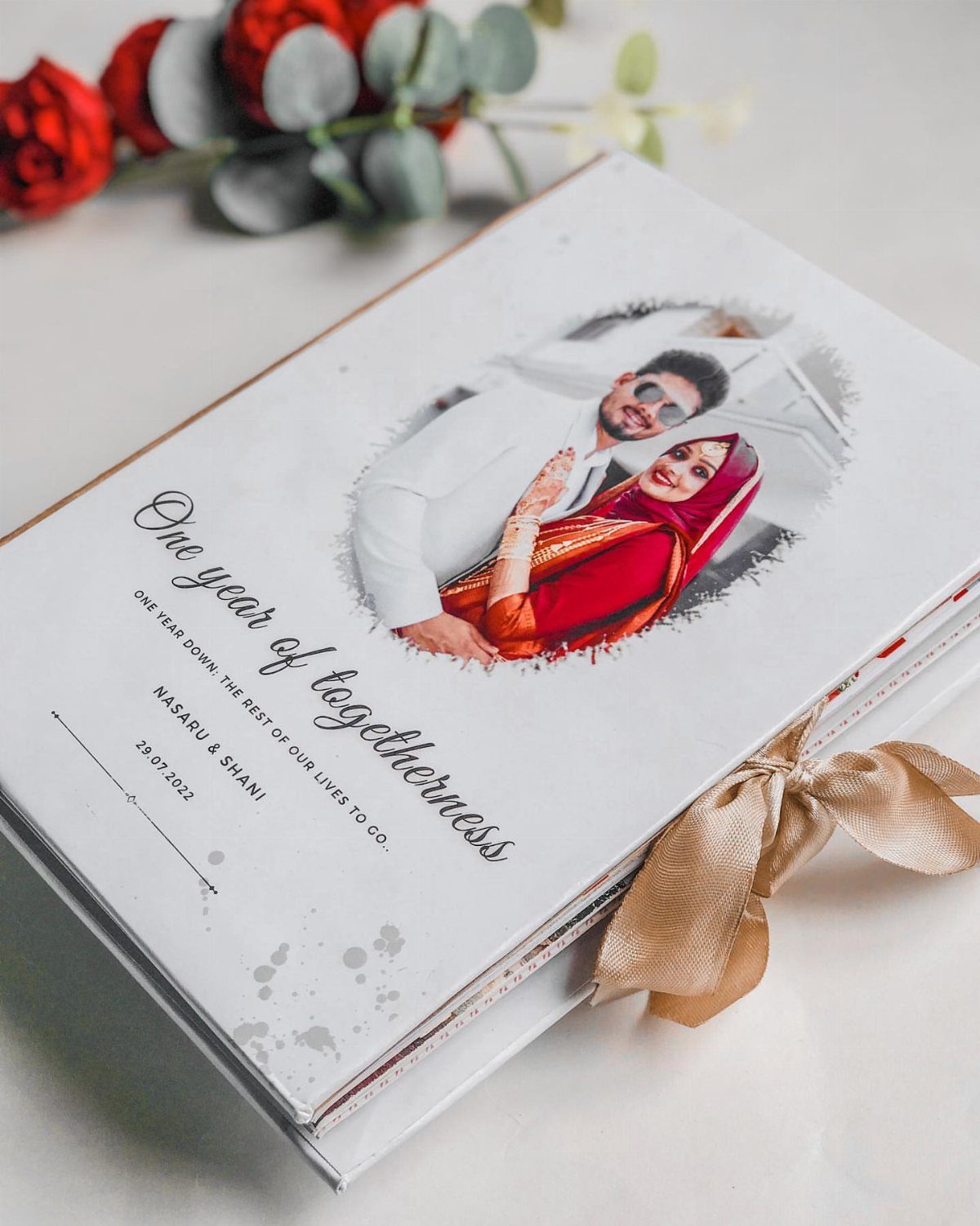 White wedding photo album with a couple's picture and gold ribbon tie.