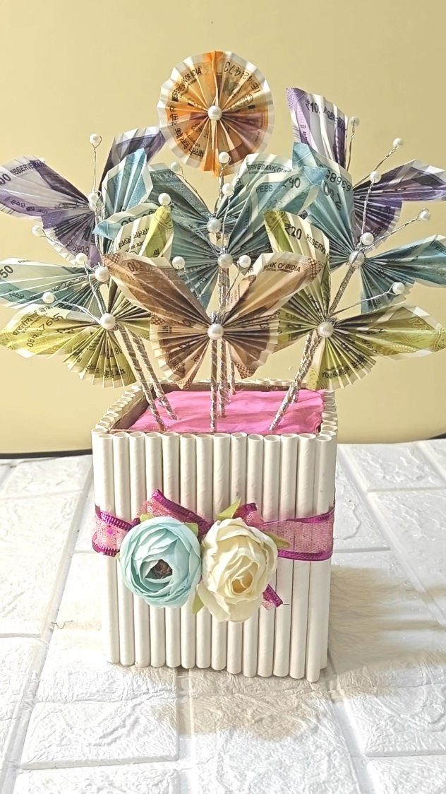 Folded banknote butterflies and flower in a white wooden box with roses.