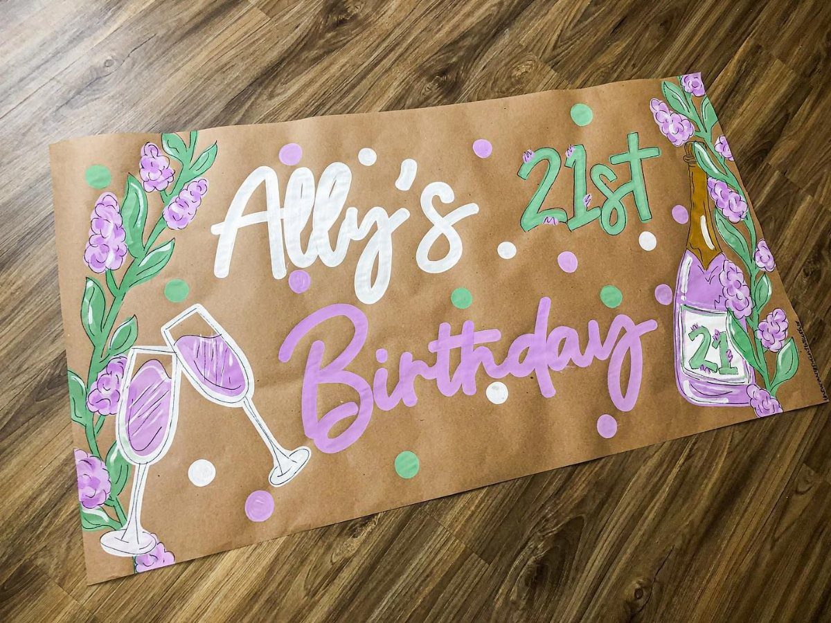 Hand-painted birthday banner with purple floral accents, champagne glasses, and 21st birthday text.