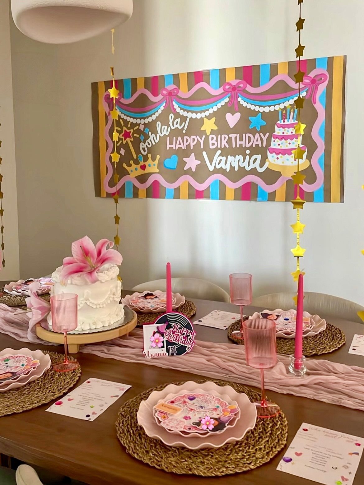 Birthday table setting with a painted banner featuring pastel stripes and pink wavy border.