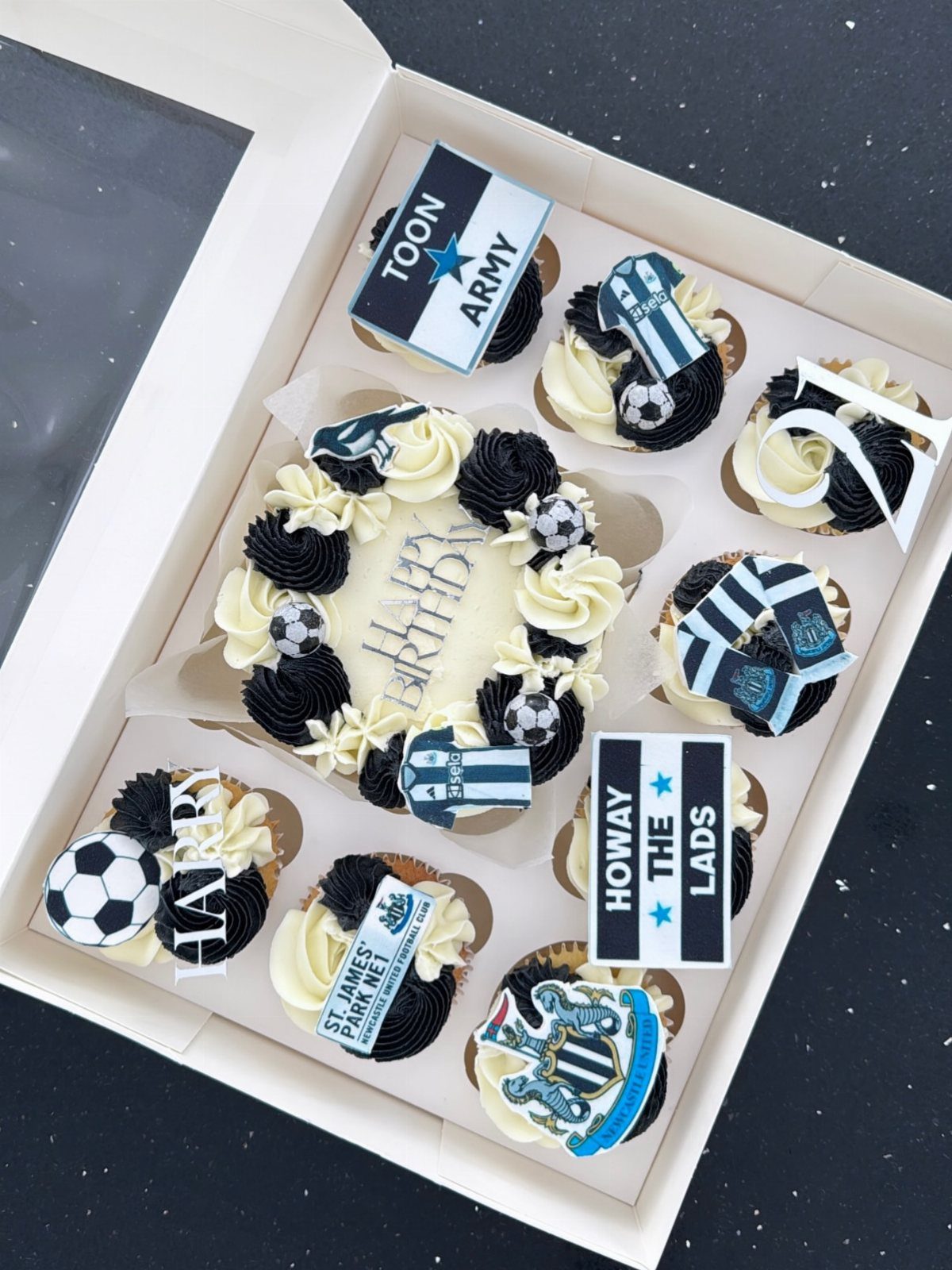Football themed birthday cake and cupcakes in a white box with team decorations.