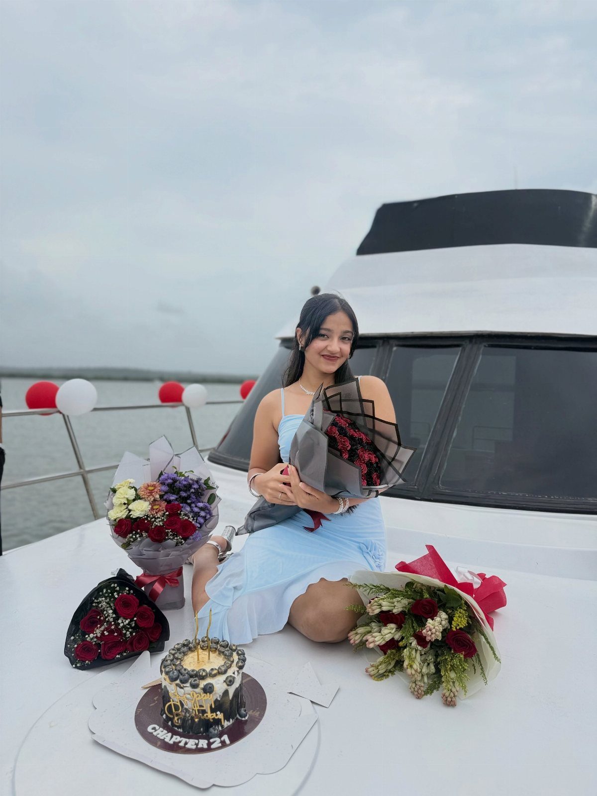 Young woman in blue dress celebrating 21st birthday on a white boat deck