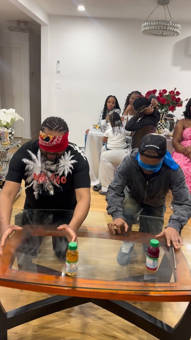 Two blindfolded men playing a game at a table during a party.