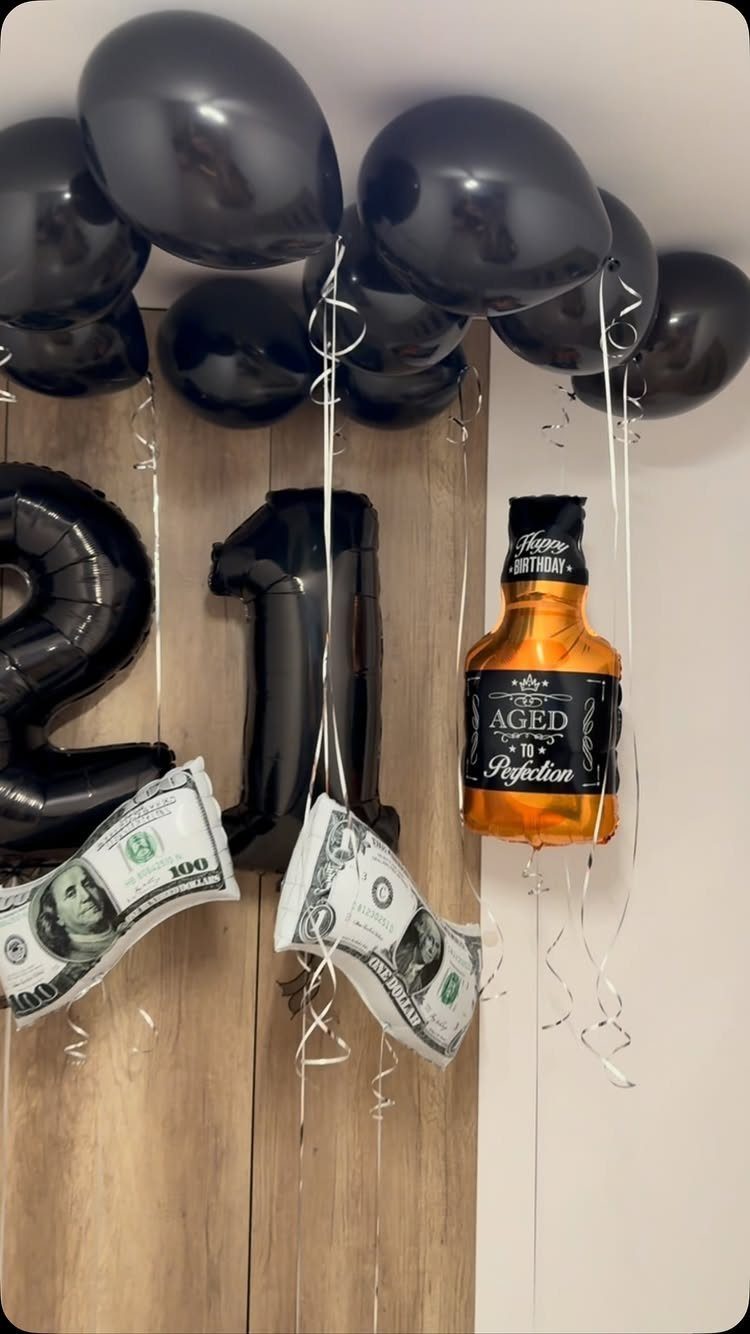 Black balloons and number 21 foil balloons with whiskey bottle and money decorations.