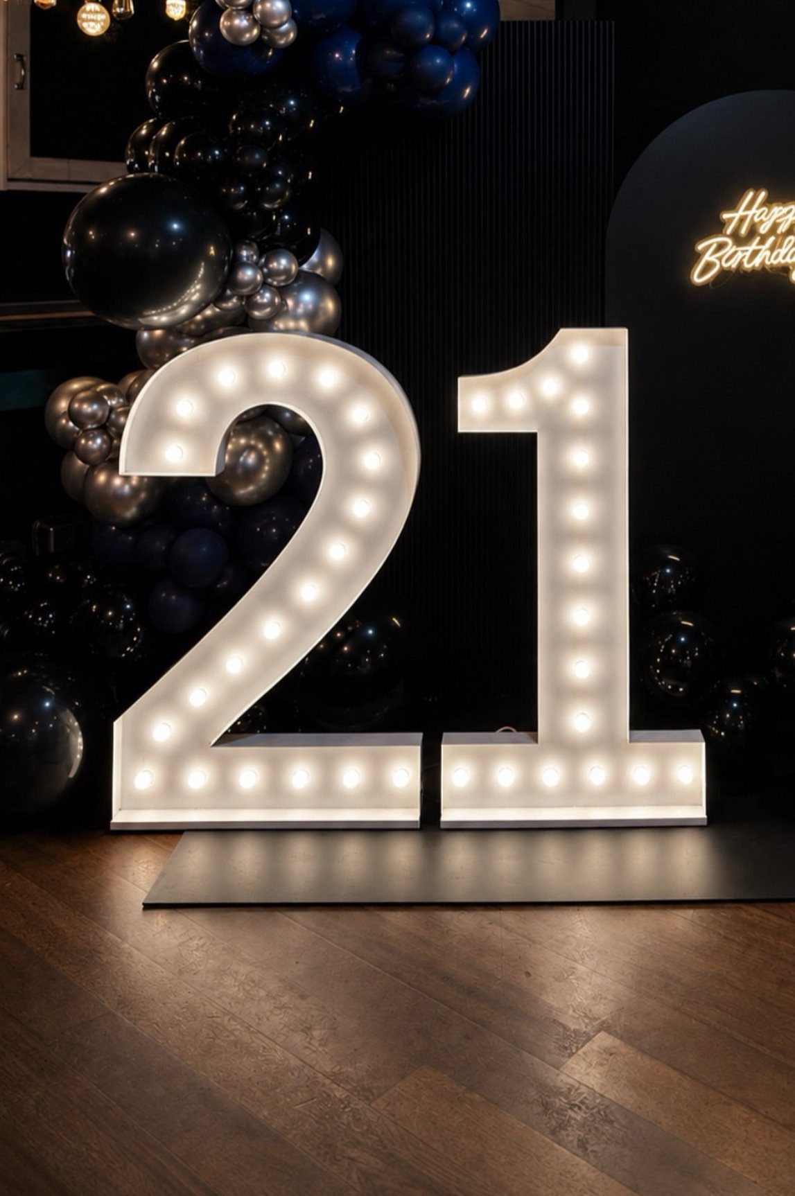 Large illuminated number 21 marquee signs surrounded by black and silver balloons.