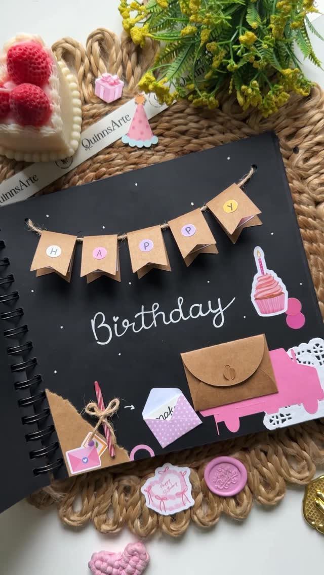 Black spiral birthday book with a brown paper banner and decorative envelopes.