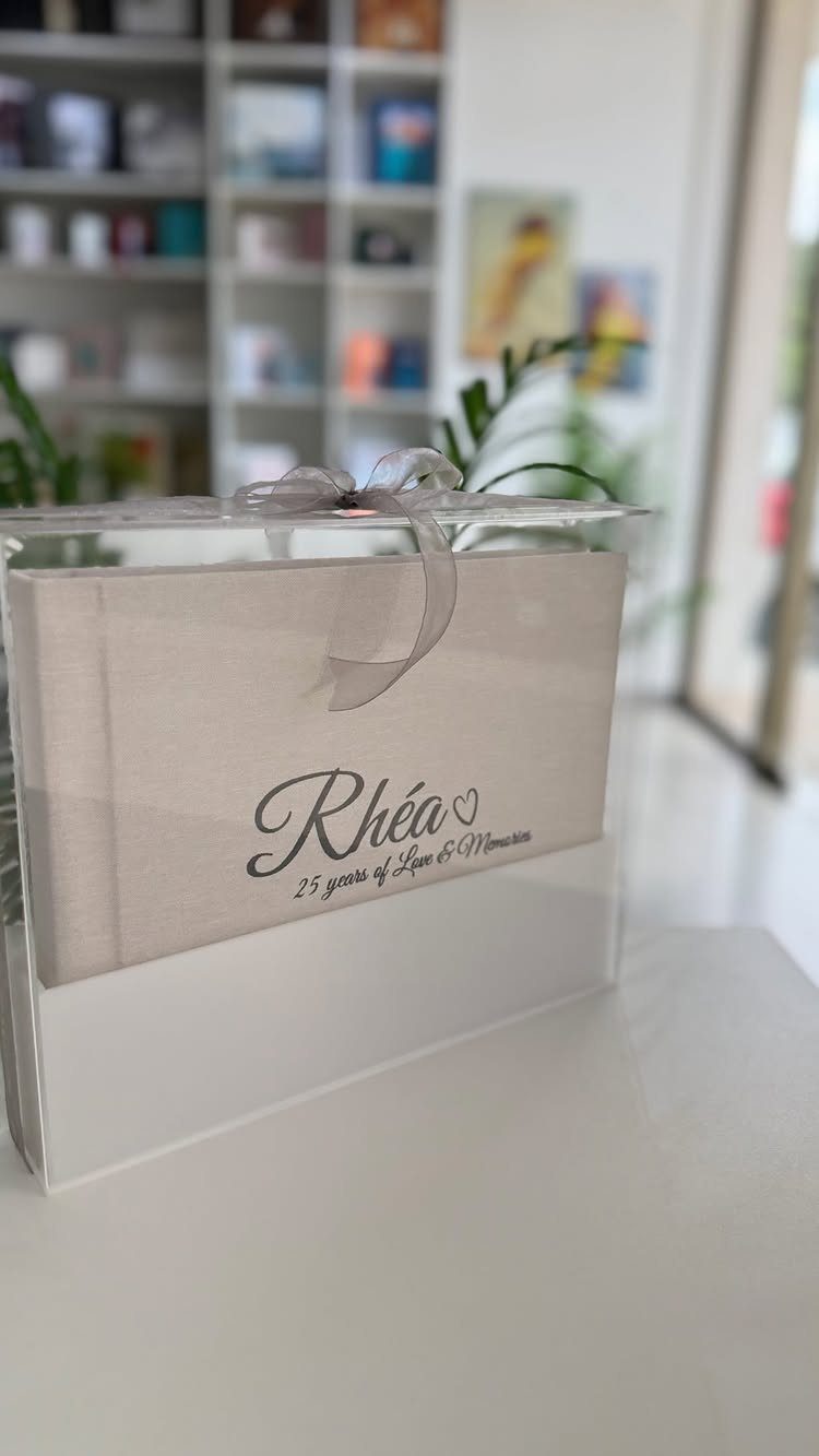 Grey photo book for 25th anniversary inside a clear acrylic box with silver ribbon.