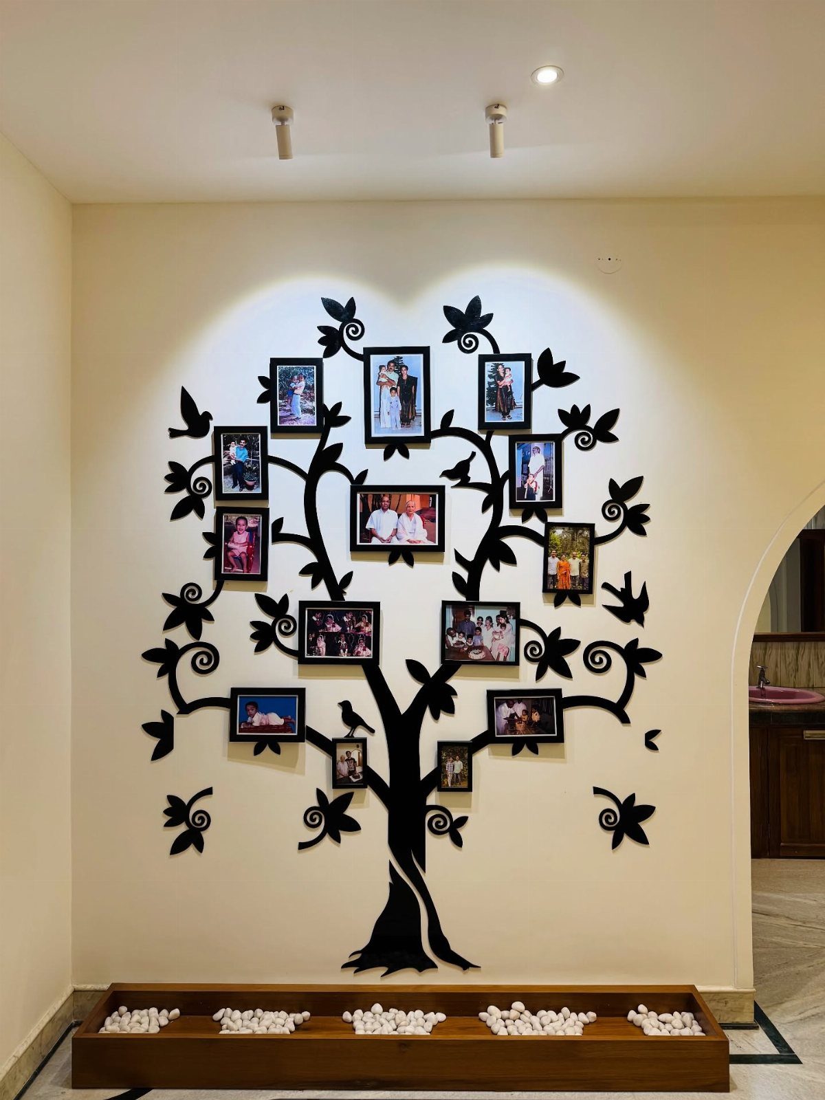 Black tree silhouette wall decal with framed family photos arranged on the branches.