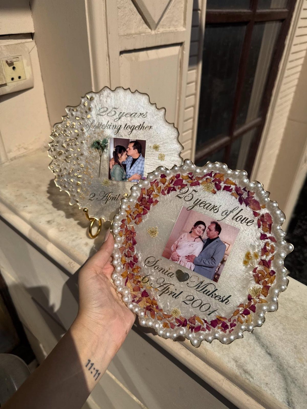 Two personalized 25th anniversary plates with photos, pearls, and dried flower petals.