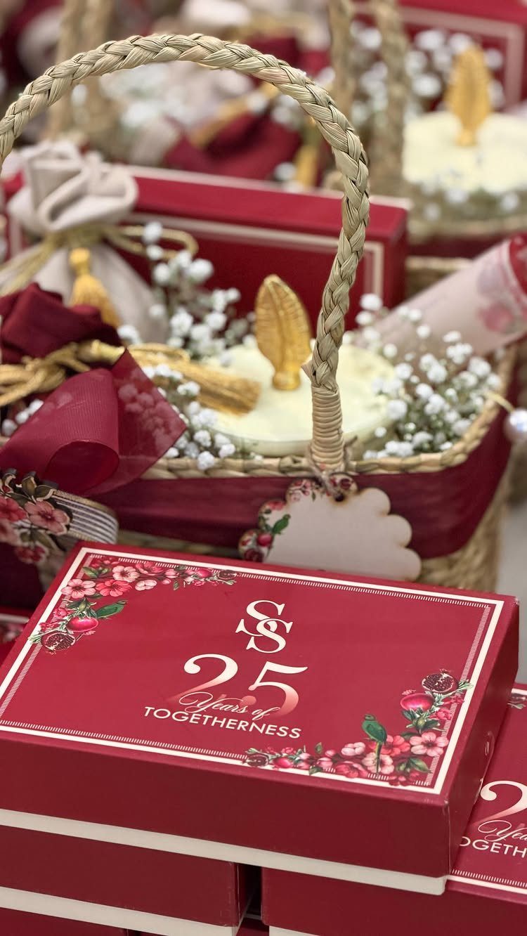 Red 25th anniversary gift box with silver text and floral accents near a basket.