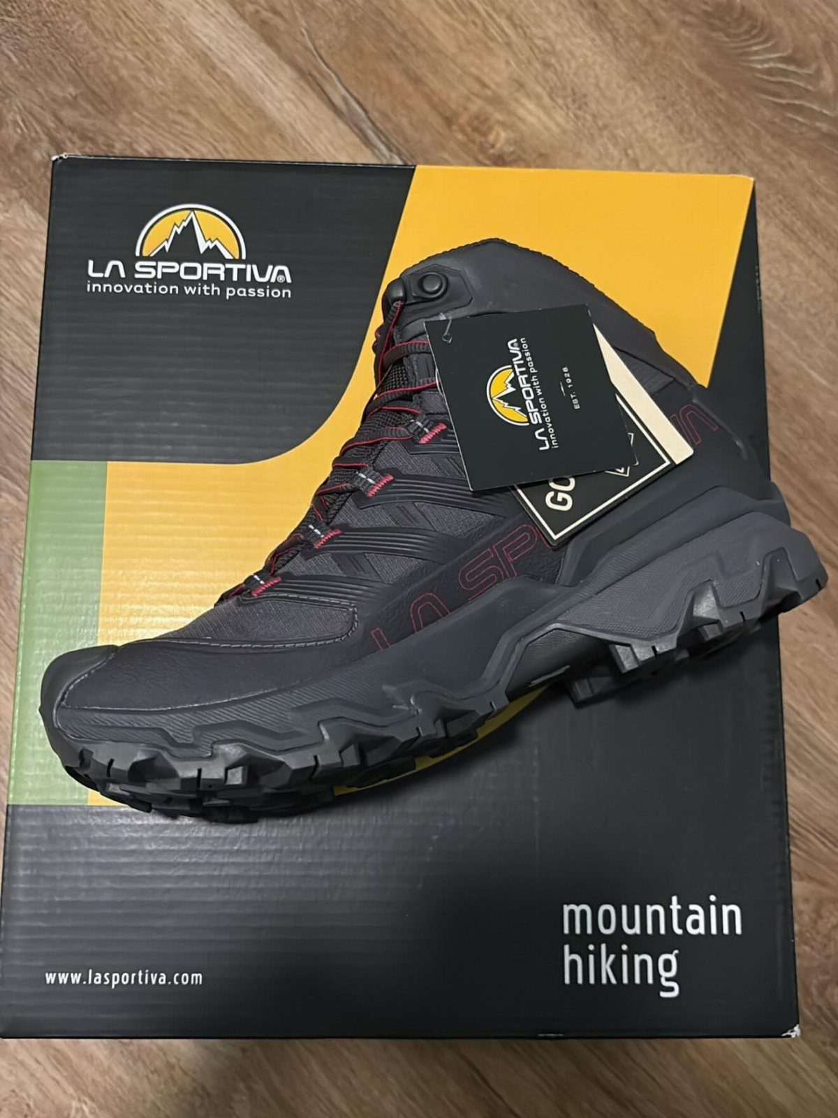 Grey La Sportiva hiking boot resting on its yellow and black branded box.