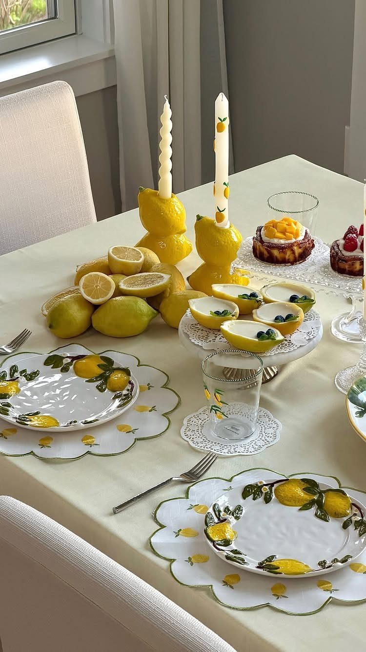 Lemon themed table setting with yellow plates, fresh lemons, and small desserts.