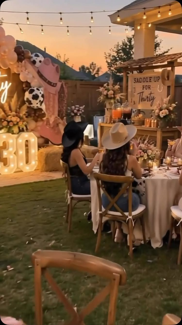 Two women at a western themed 30th birthday party with balloons and lights.