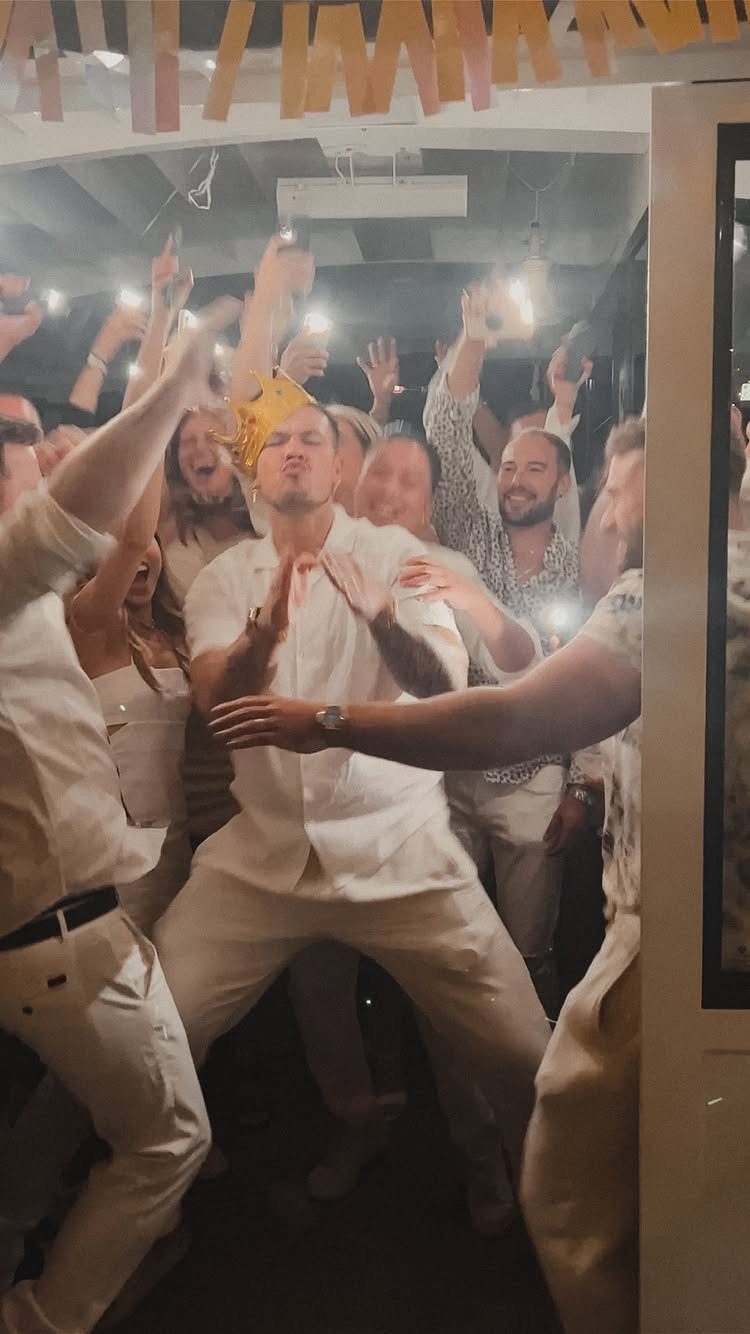 Group of friends in white outfits dancing and celebrating at a party.