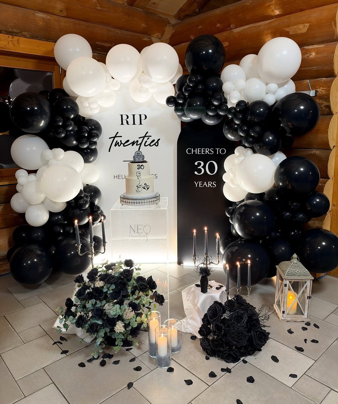 Black and white birthday party decor with balloons, RIP twenties sign, and cake.
