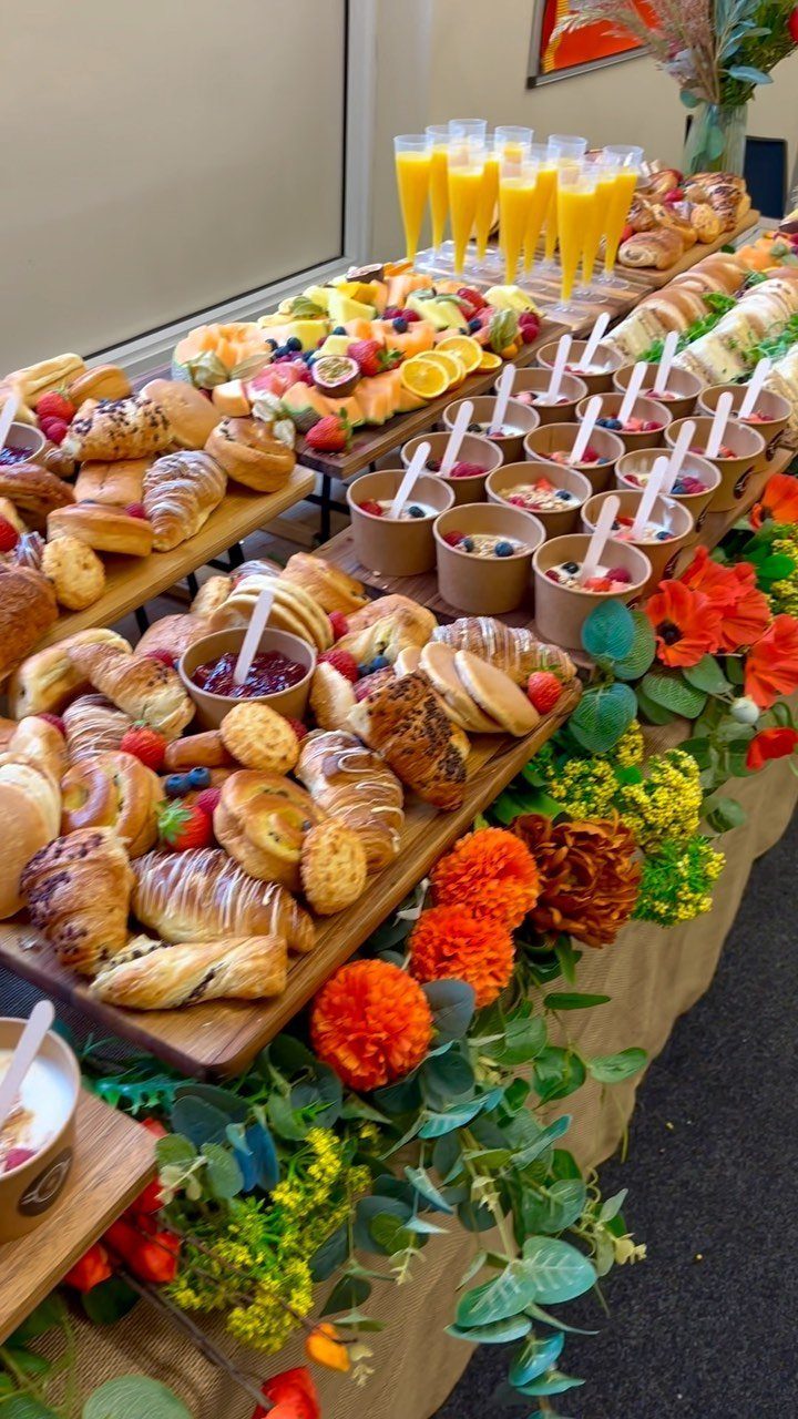 Brunch spread with pastries, fruit, and orange juice decorated with bright flowers