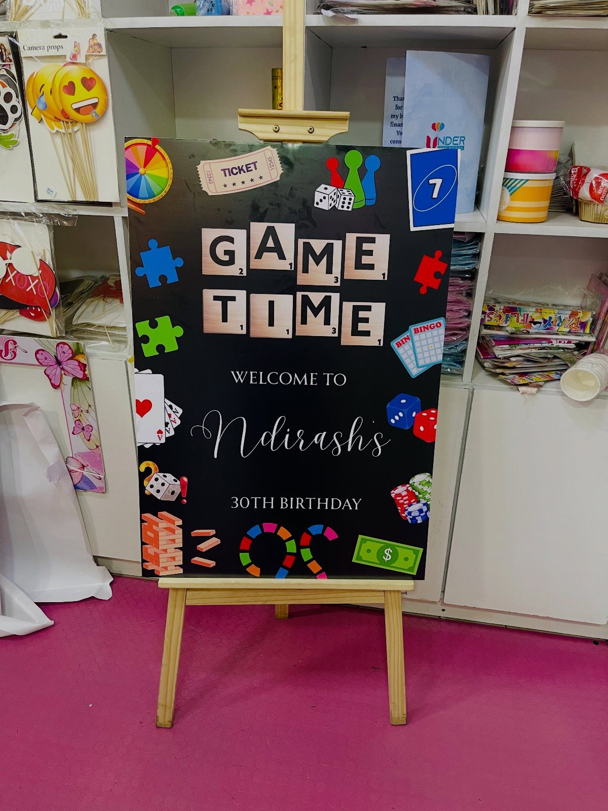 Black welcome sign for a 30th birthday game night on a wooden easel