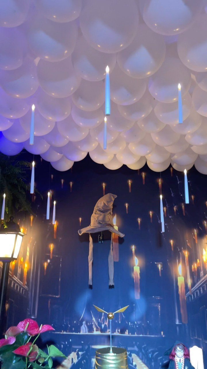 Wizarding world party decor with white balloon ceiling and floating candle mural