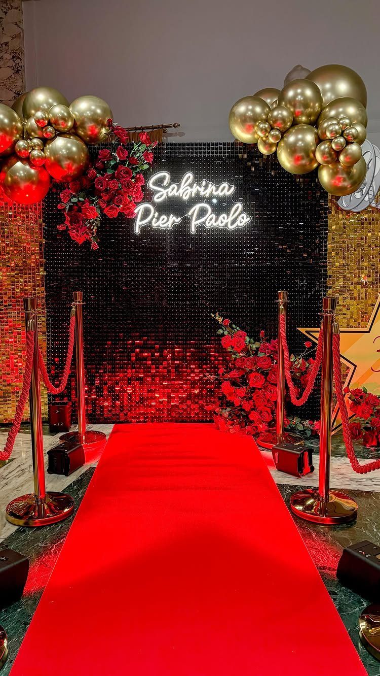 Red carpet entrance with gold balloons, red roses, and a black sequin backdrop.