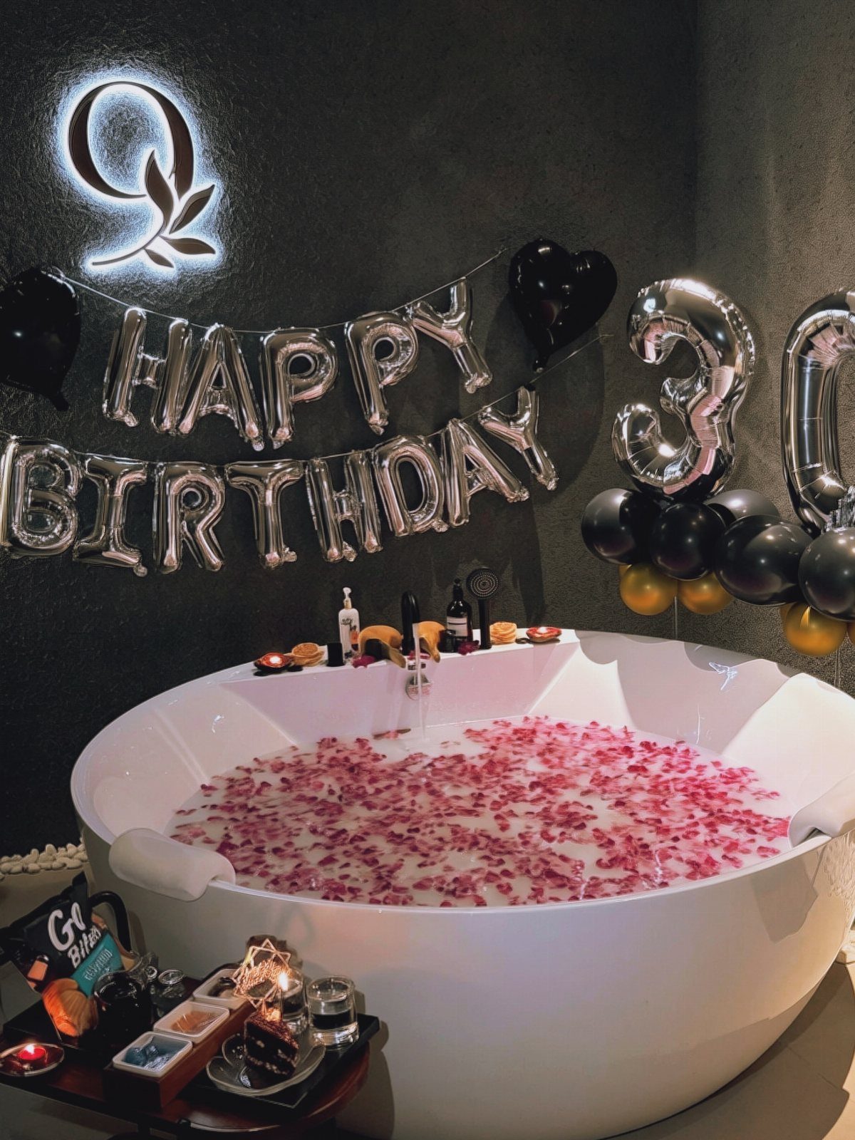 White bathtub filled with pink petals and milky water for a 30th birthday