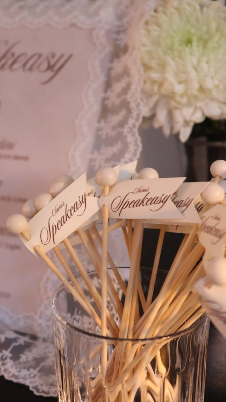Speakeasy themed party flags in a glass with lace and flowers background
