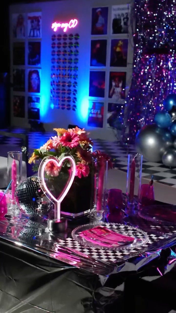 Party table with neon heart, disco ball, and nostalgic photo wall background