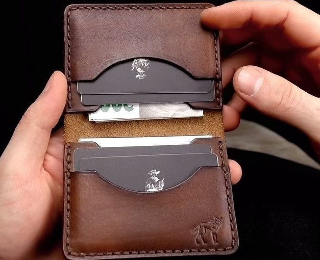 Brown leather wallet held open showing credit cards and cash inside.