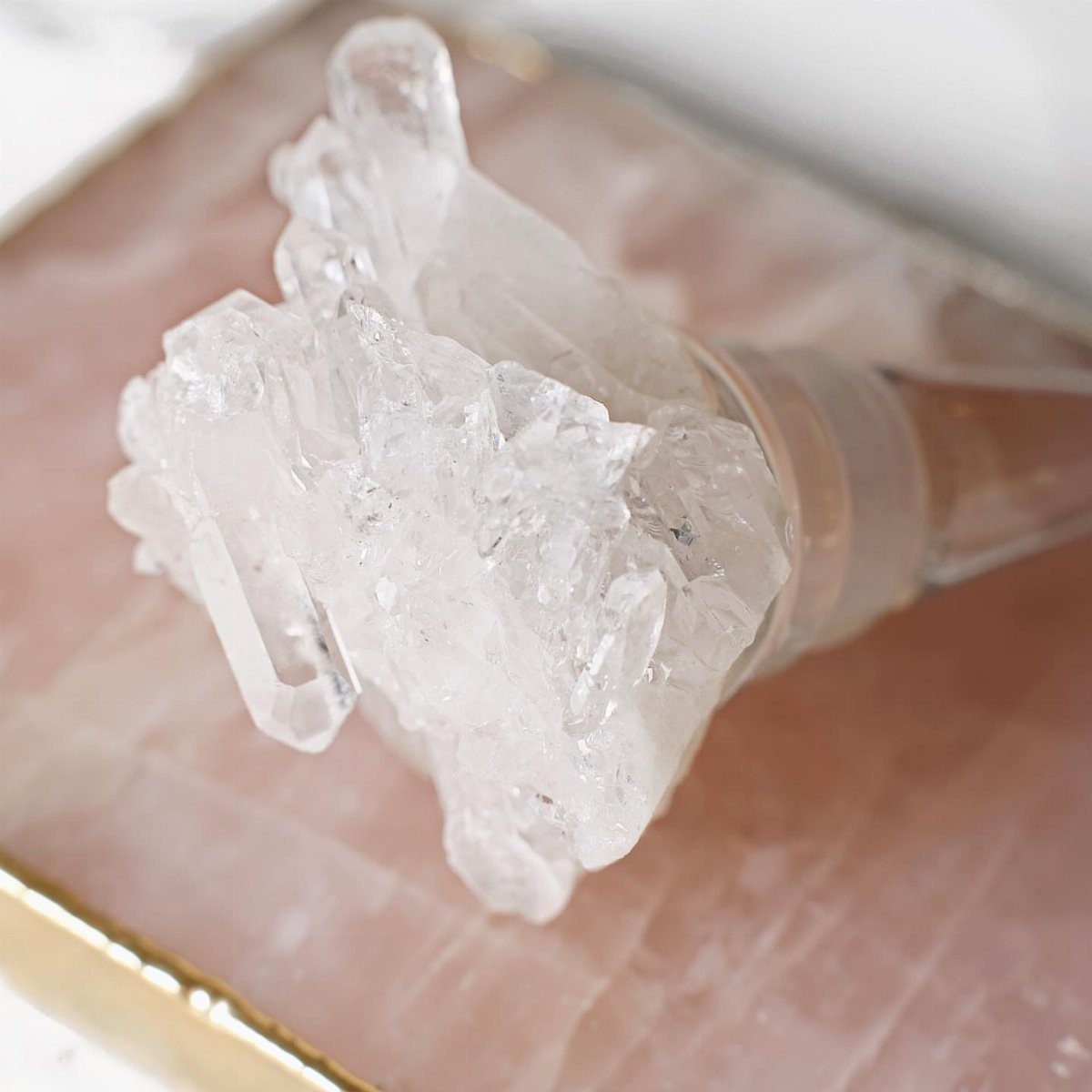 Crystal wine stopper with a raw quartz cluster on a pink quartz slab.