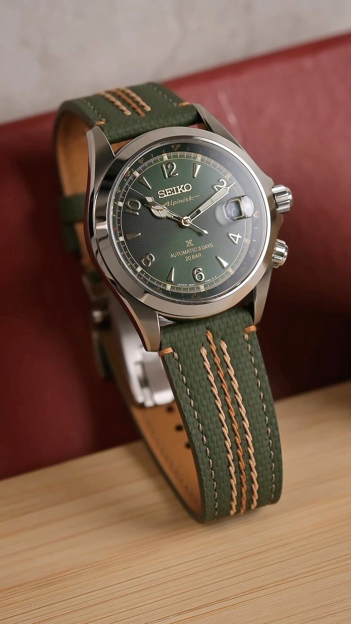 Seiko wristwatch with a green leather strap and tan stitching on wooden surface