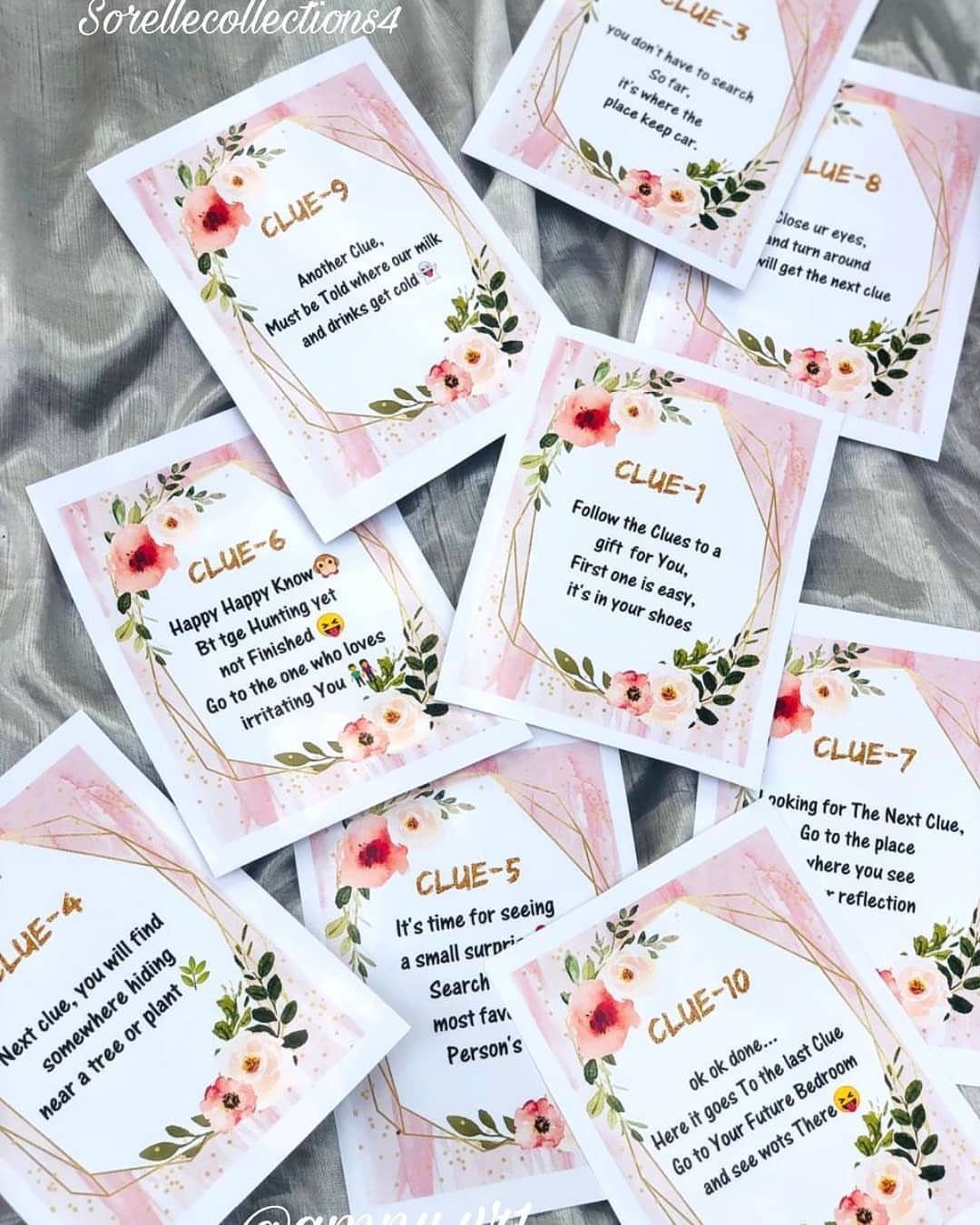 Scavenger hunt clue cards with floral borders scattered on a grey fabric background.