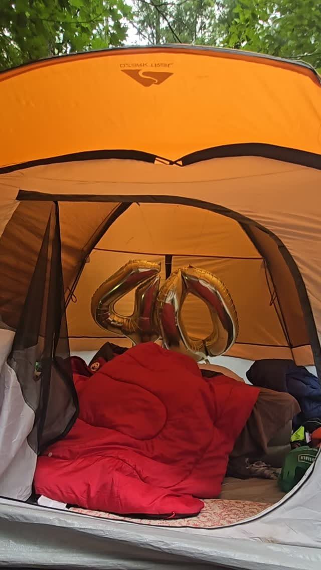 Gold number 40 balloons inside an orange camping tent with a red sleeping bag.