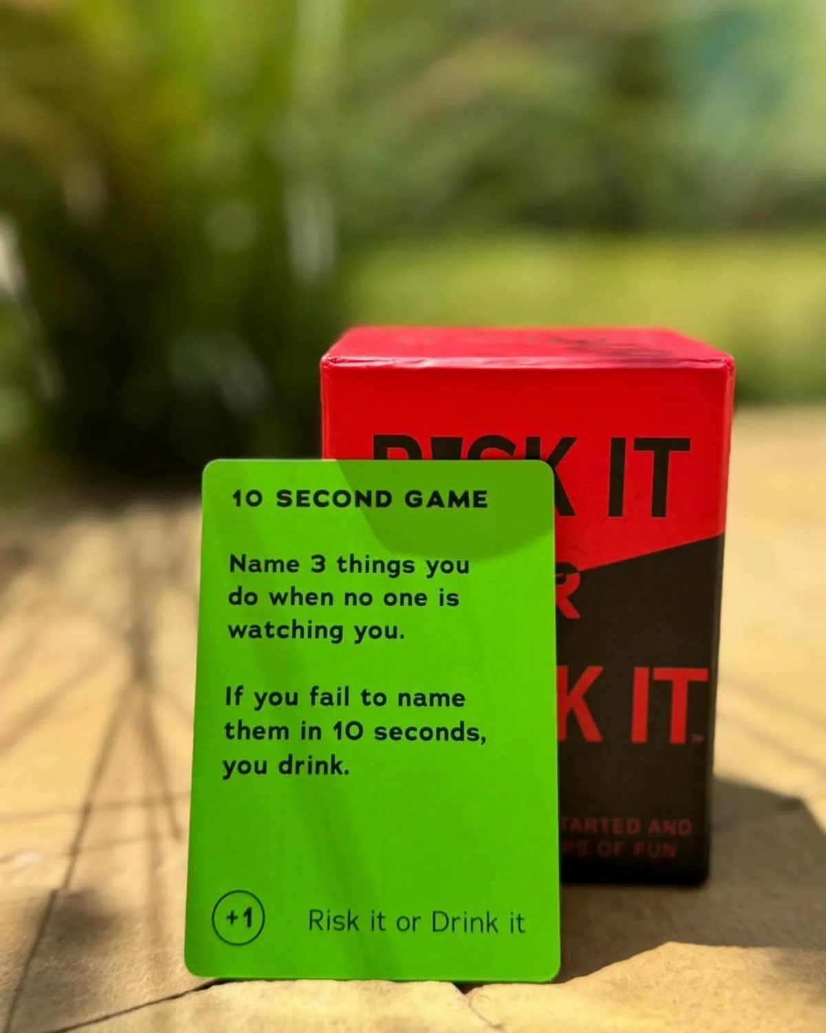 Risk It or Drink It card game box and green prompt card outdoors