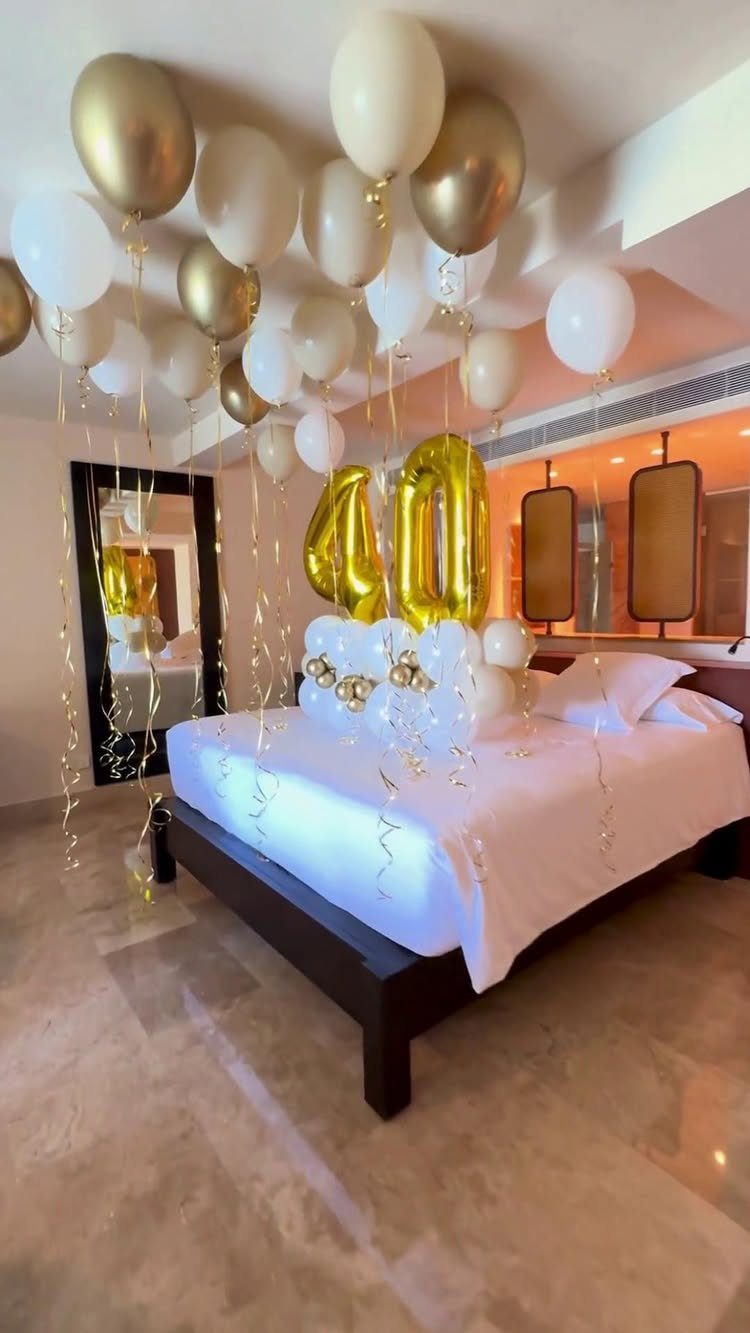 Hotel bed decorated with gold and white balloons and a gold number 40