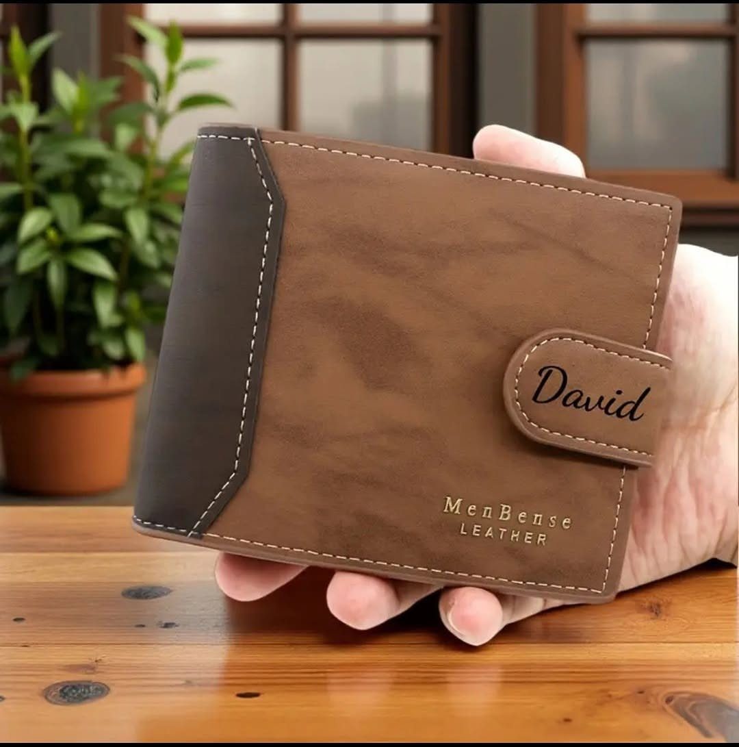 Brown leather wallet engraved with the name David held in a hand