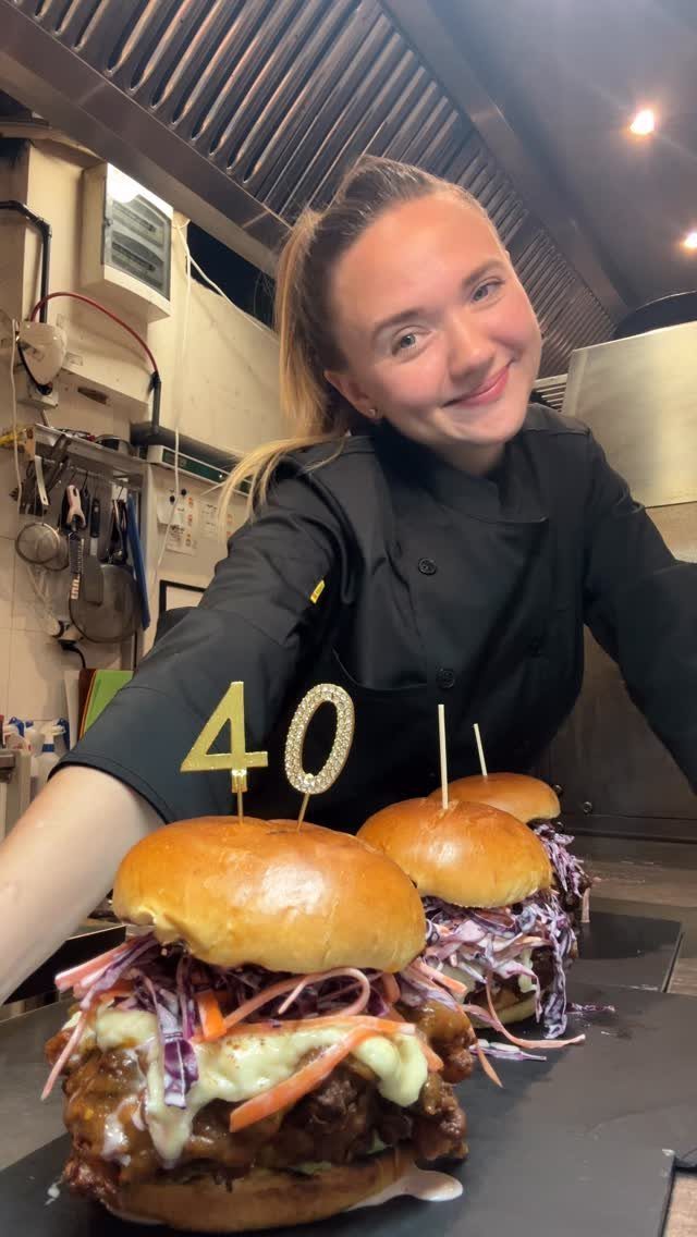 Chef smiling behind two gourmet burgers with a gold 40th birthday topper.