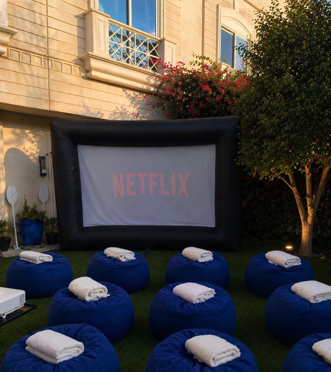 Outdoor cinema setup with a large inflatable screen and blue bean bag chairs.