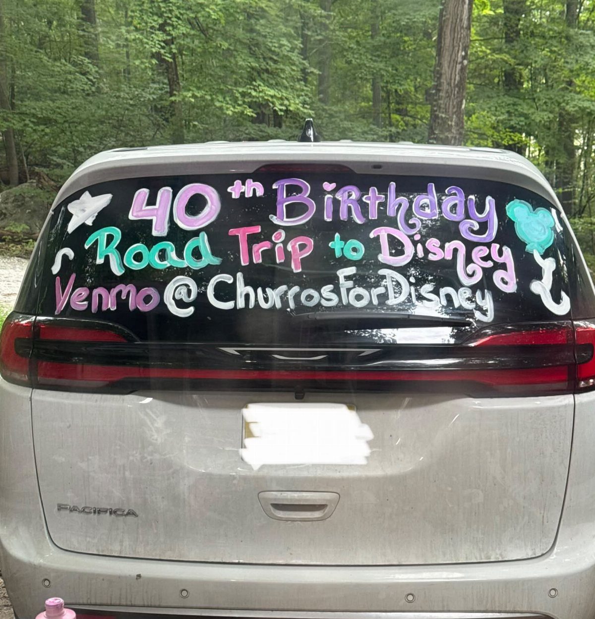 Silver minivan with 40th birthday road trip message written on the rear window