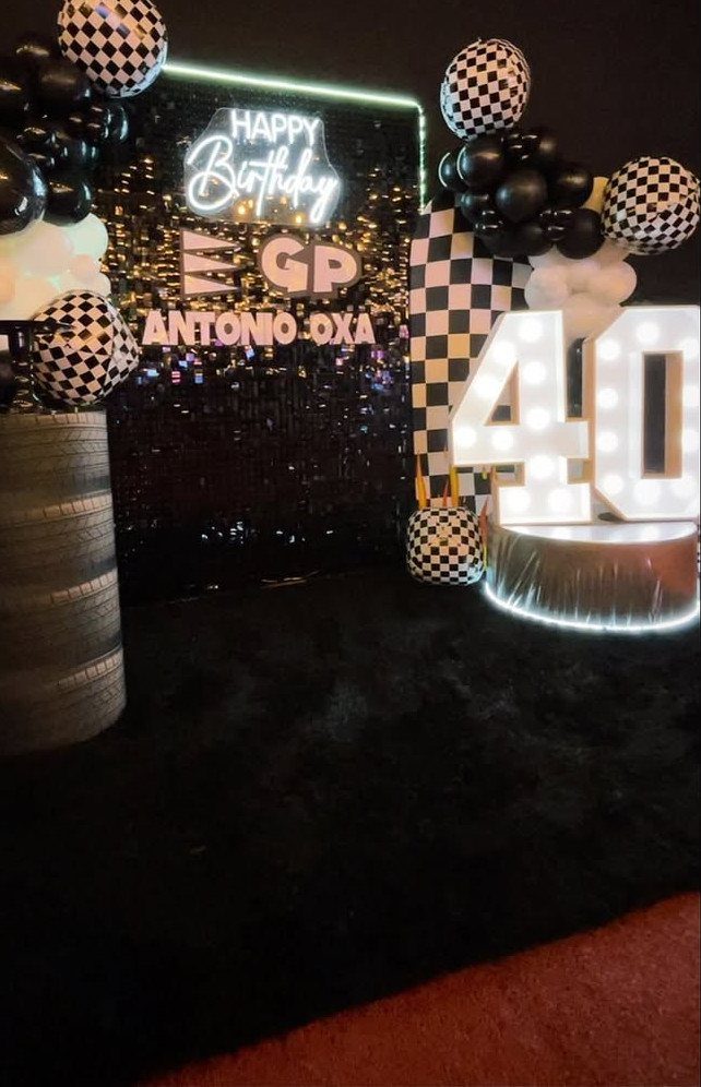 Racing-themed 40th birthday party decoration with checkered balloons and large glowing numbers.