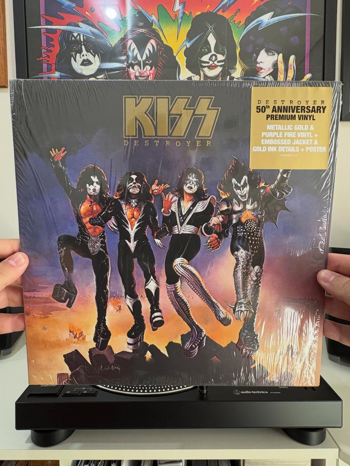 KISS Destroyer 50th anniversary vinyl record held over a black record player.